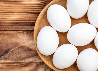 Wooden bowl with eggs on the table. Top view. Copy space.