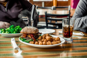 a great all american beef and jalapeno burger with bacon, side of brocculi and a coke
