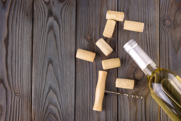 Glass bottle of wine with corks on wooden table background.