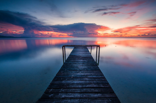 wooden jetty toward horizon during sunset. image contain soft focus and blur due to long expose.