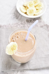 Healthy drink milkshake with banana in glass on stone table.