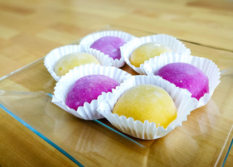 Colourful Japanese Mochi in a transparent plate on wooden background.