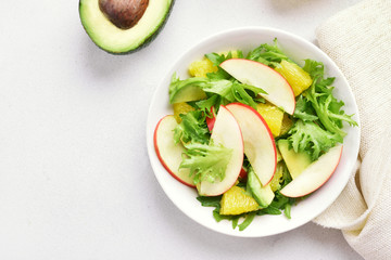 Fruit vegetable salad with red apples, avocado, orange slices