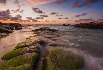 rocks covered by green moss and thick clouds during sunset.