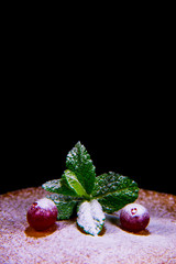 Berry cranberries lie on pancake with mint sprinkled with powdered sugar on a black background.
