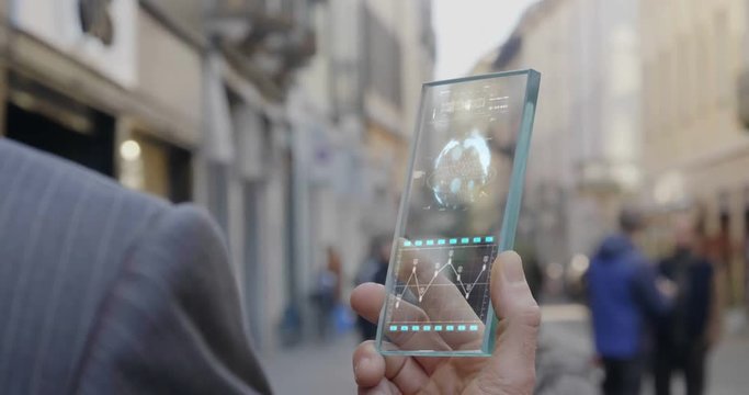 A man answers the wife who smiles and waves from the phone that appears in hologram clock futuristic and technological. Concept: holiday, communication,family, technology, augmented reality and future