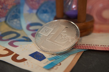 Silver litecoin lying on the euro banknotes