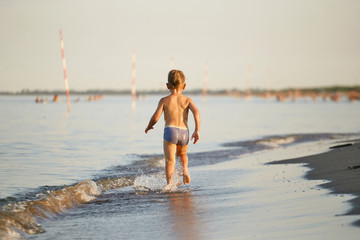 water fun. the boy runs along the seashore