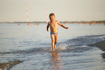 Fototapeta premium water fun. the boy runs along the seashore