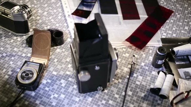 Medium format camera, film strips and contact sheet on table.
