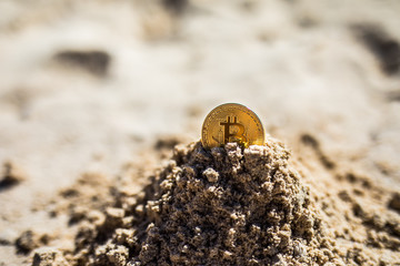 Bitcoin. Bitcoin on golden sand, in background sea. Concept freelance, stock exchange.