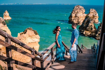Happy young couple men and woman at the beautiful cliffs and rocky coastline of the Algarve by...