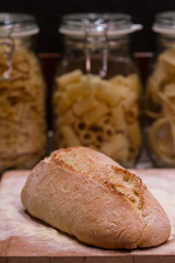 Bread laid on a chopping board, with pasta bowls in the background