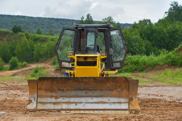 Fototapeta na wymiar Tractor bulldozer on a caterpillar drive is parked in the mud. Concept road construction.