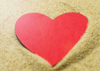 Red heart on sand.