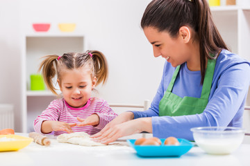 Fototapeta premium Happy mother and daughter are making cookies in their kitchen. 