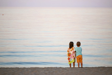 children boy and girl romance on the seashore colorful sunset.