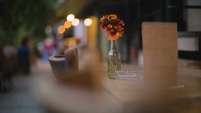 Bunch of flowers on reserved table in restaurant with outdoor seating, evening