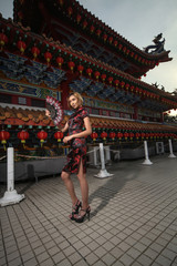 asian lady wearing traditional cheongsam dress with temple and lantern background