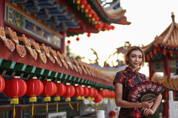 asian lady wearing traditional cheongsam dress with temple and lantern background