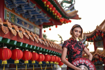 Fototapeta premium asian lady wearing traditional cheongsam dress with temple and lantern background