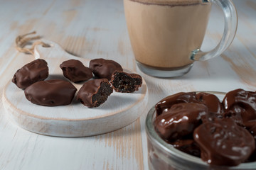 Prunes in chocolate on wooden background.