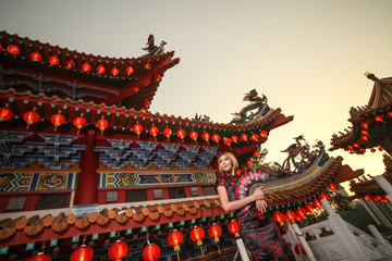 Fototapeta na wymiar asian lady wearing traditional cheongsam dress with temple and lantern background