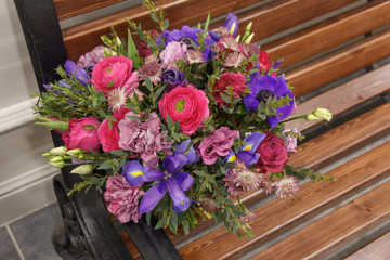 Beautiful designer red purple blue bouquet of florist with different flowers on wooden bench