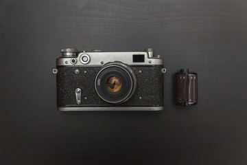 Vintage Film Camera And Roll On Black Wooden Background Technology Development Photographer Concept...
