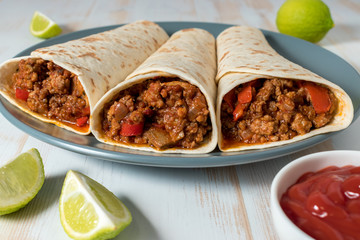 Tasty homemade burrito with vegetables and beef on plate.