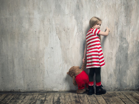 A punished child standing by the wall.