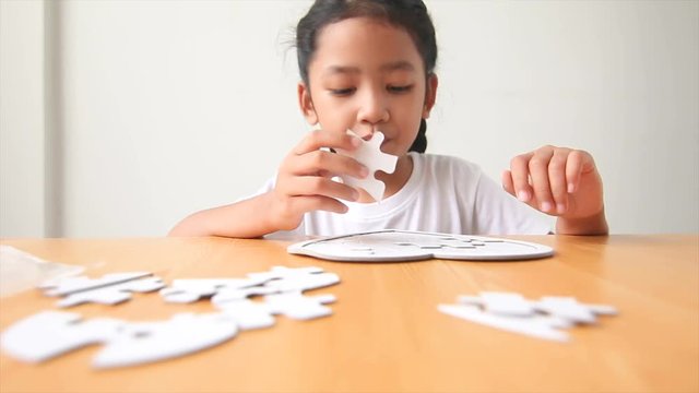 Asian little girl playing jigsaw puzzle select focus on hand shallow depth of field