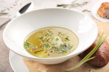 chicken soup with bread in white plate on a white wooden background