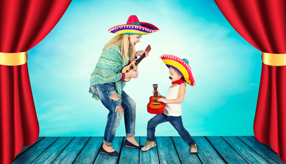 Mexican party. A small boy in a sombrero plays the guitar and sings a serenade for his mother.	
