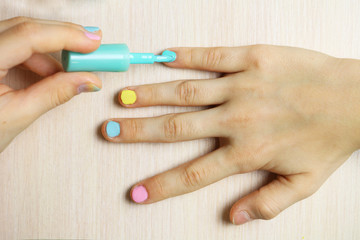 Girl Putting On Multicolor Nail Polish On Finger Nails