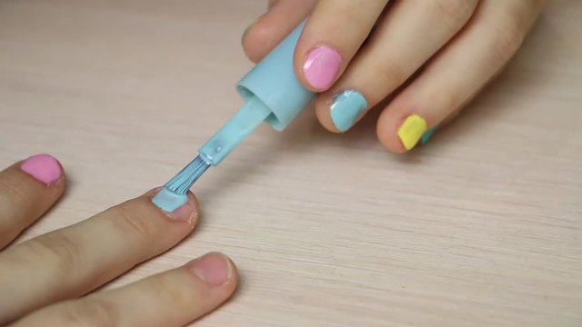 Girl Putting On Multicolor Nail Polish On Finger Nails