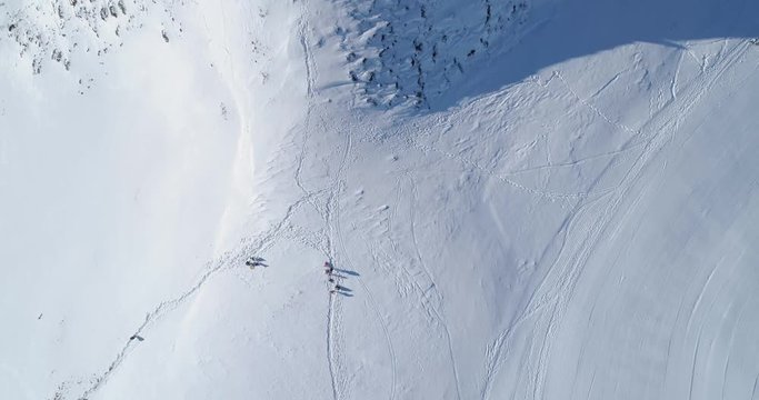 Overhead aerial top view over winter snowy mountain ski track field with people in sunny day.Above Alps mountains snow season establisher.4k drone flight establishing shot straight-down perspective