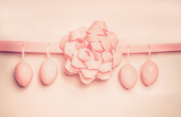Easter eggs hanging on pink ribbon with bow , pastel color