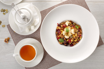 muesli on a white plate on white wooden background