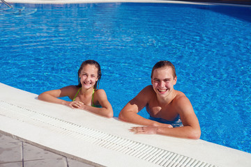 boy and girl having fun in swimming pool