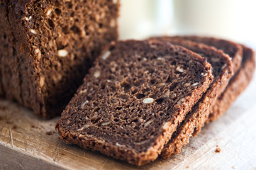 Whole-wheat bread with seeds cut on a wooden board on a natural background. Healthy food, healthy food.