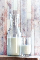 bottle of milk and a glass of milk on a natural, wooden background. Breakfast, natural rustic food