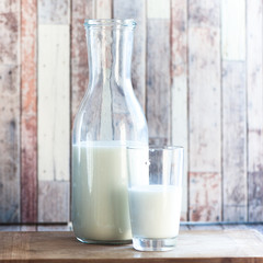 bottle of milk and a glass of milk on a natural, wooden background. Breakfast, natural rustic food