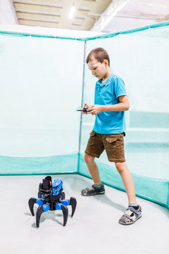 School boy playing with robot toy spider by remote control