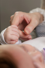 Newborn baby holding mother's finger
