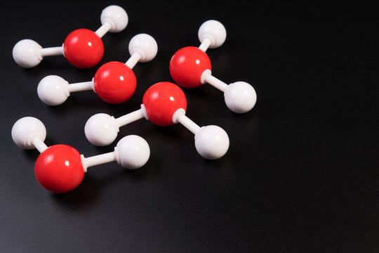 Chemistry model atom of molecule water scientific elements. Integrated particles hydrogen and oxygen atom on black background. Chemistry conceptual plastic model for education.