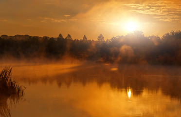 wonderful misty evening. majestic golden sunset over the foggy lake