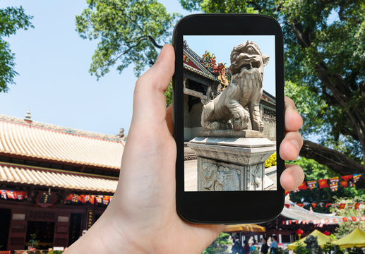 tourist photographs lion statue in Guangzhou city