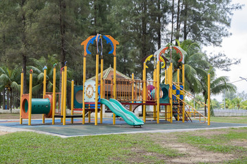 Colorful children playground in public park surrounded by green trees