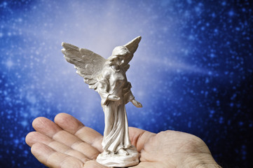 angel statue on  hand palm and divine rays of light 